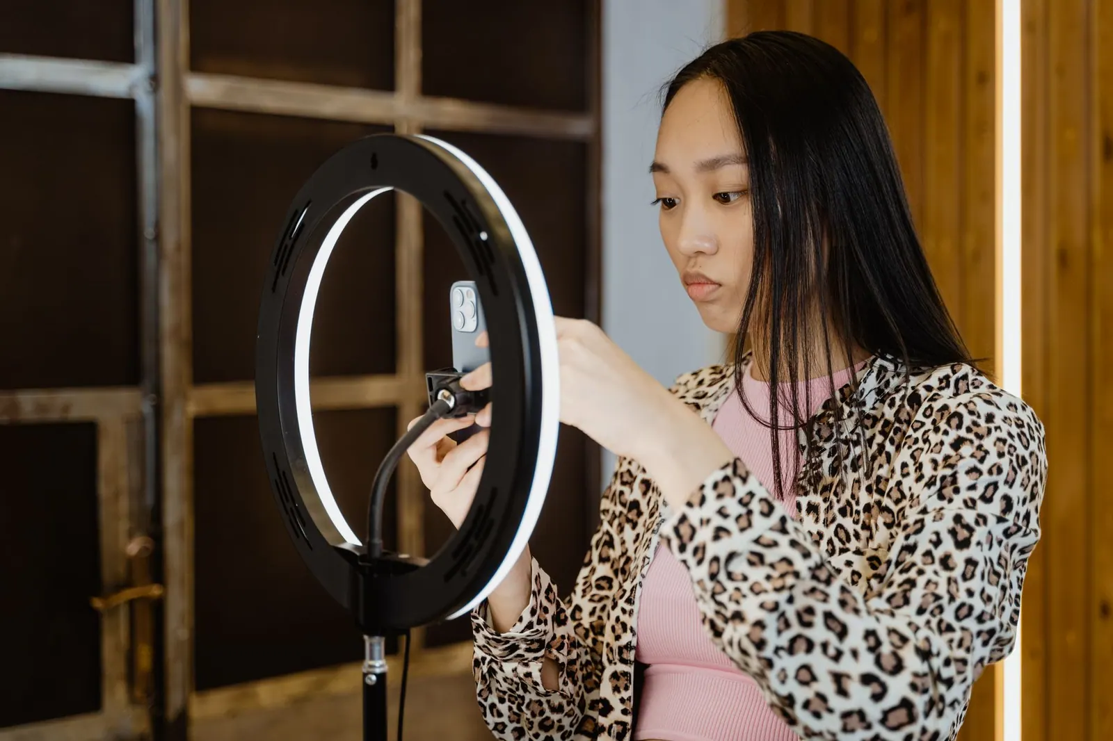Asian woman with leopard print jacket adjusts ring light for smartphone streaming setup. Is signature really the hard part of a disclosure record?