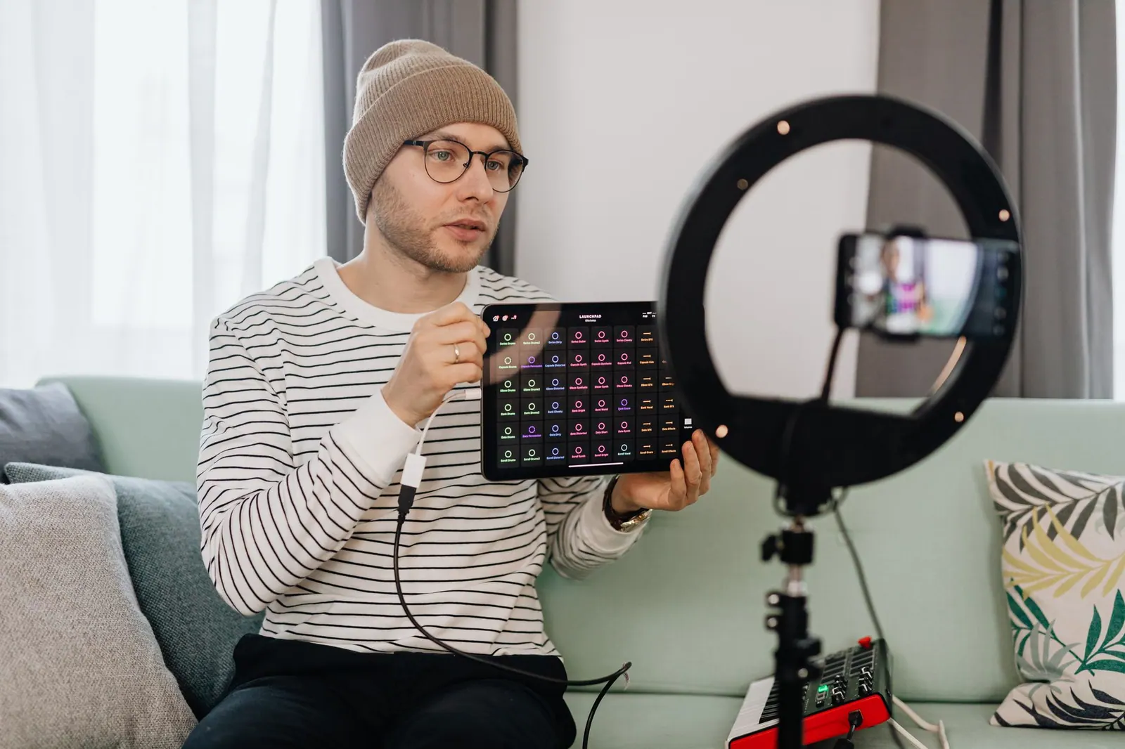 Adult man wearing a beanie records a tech review vlog indoors using a smartphone and ring light. Which rates and negotiation platforms are worth the fee