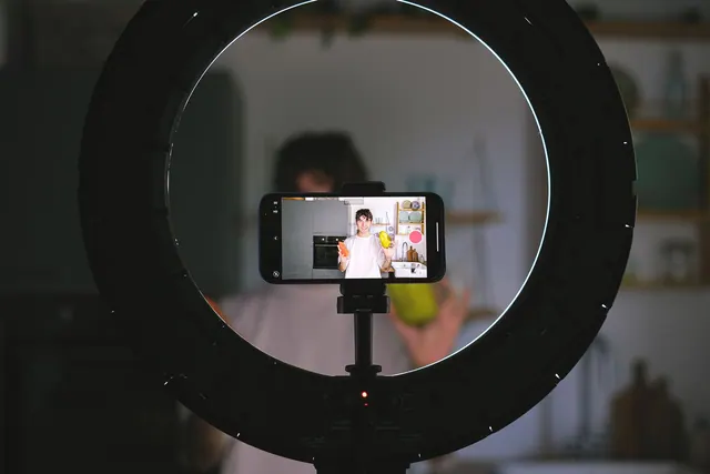 A food blogger records a video using a smartphone and ring light in a kitchen setting. Campaign briefs: methods, tools and useful context