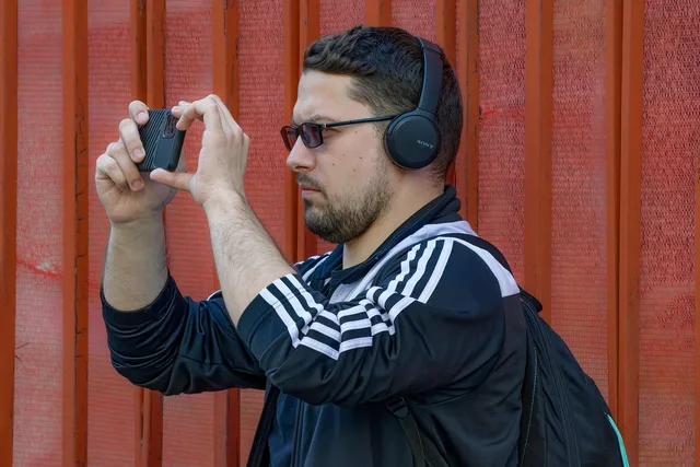 man, adult, casual, beard, backpack, smartphone, outdoors, lifestyle, photography, filming. Illinois influencer sponsor partnerships vs. California and New York